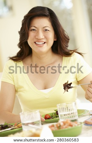 Asian woman eating meal at home