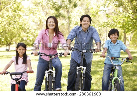 Asian family riding bikes in park