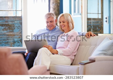 Mature Couple At Home In Lounge Using Laptop Computer