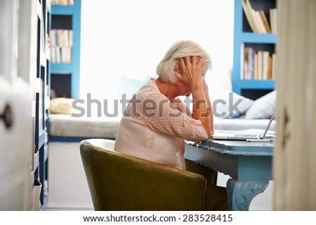 Stressed Senior Woman At Desk In Home Office With Laptop