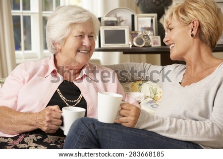 Adult Daughter Visiting Senior Mother Sitting On Sofa At Home