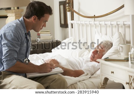 Doctor Talking With Senior Male Patient In Bed At Home