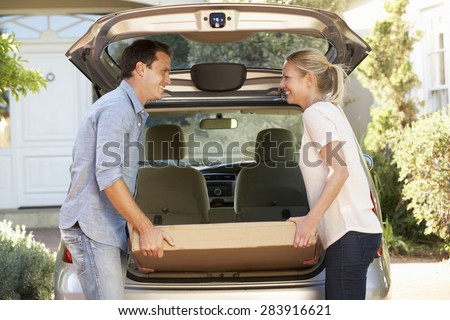 Couple Loading Large Package Into Back Of Car