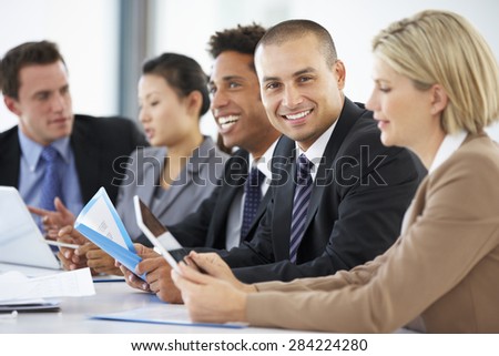 Portrait Of Male Executive Attending Office Meeting With Colleagues