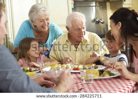 Multi Generation Family Eating Meal Together In Kitchen