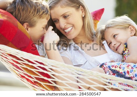 Mother And Children Relaxing In Garden Hammock Together