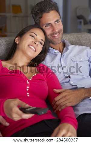 Hispanic Couple On Sofa Watching TV Together