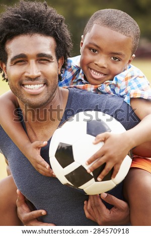 Father With Son Playing Soccer In Park Together