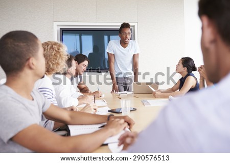 Businessman By Screen Addressing Boardroom Meeting