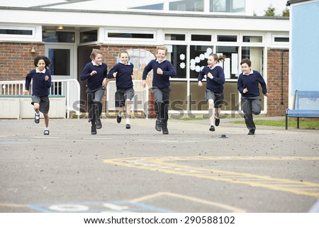 Group Of Elementary School Pupils Running In Playground