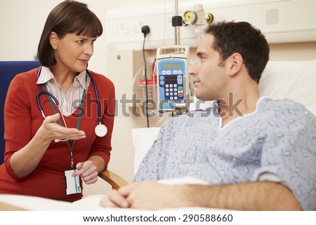 Female Doctor Sitting By Male Patient\'s Bed In Hospital