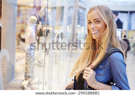 Female Shopper Looking In Store Window Inside Shopping Mall