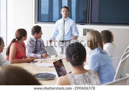 Motivational Speaker Talking To Businesspeople In Boardroom