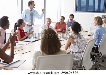 Motivational Speaker Talking To Businesspeople In Boardroom