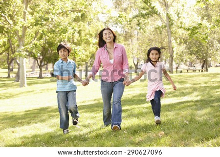 Asian mother and children running hand in hand in park