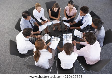 Overhead View Of Businesspeople Seated In Circle At Company Seminar