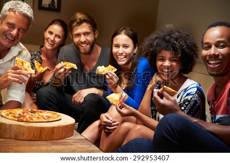 Group of adult friends eating pizza at a house party