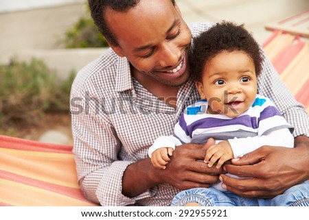 Father bonding with young son sitting in a hammock