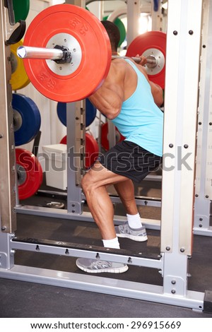 Man weightlifting barbells at a squat rack in a gym