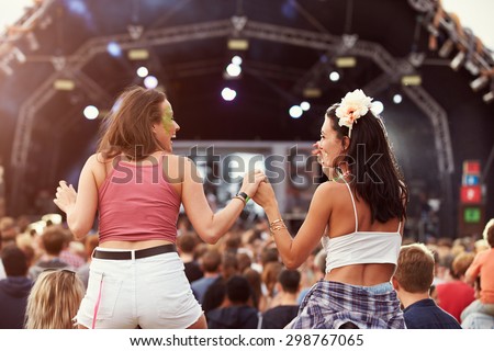 Two girls on shoulders in the crowd at a music festival