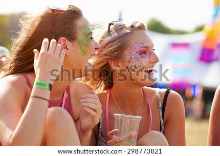 Girl friends wearing face paint at music festival, close up