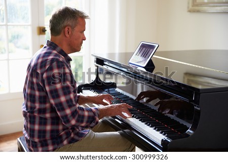 Man Learning To Play Piano Using Digital Tablet Application