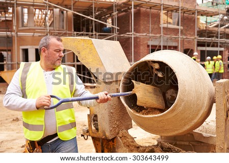 Construction Worker On Building Site Mixing Cement