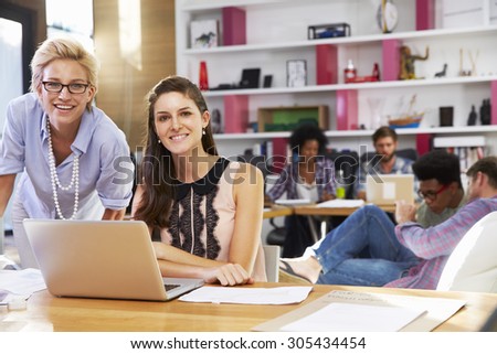 Portrait Of Businesswomen Working On Laptop In Busy Office