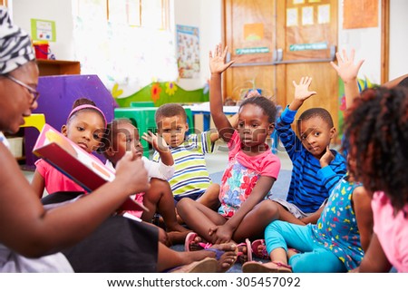 Class of preschool children raising hands to answer teacher