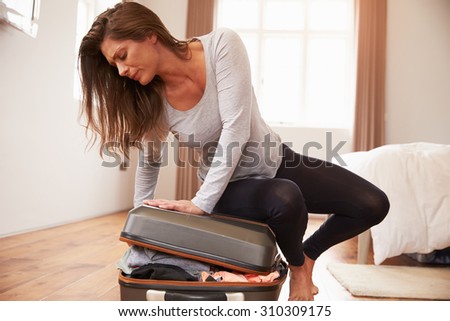 Woman Packing For Vacation Trying To Close Full Suitcase