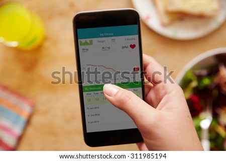 Person Eating Lunch Looking At Fitness App On Mobile Phone