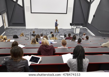Man lectures students in lecture theatre, back row seat POV 商業照片 © 