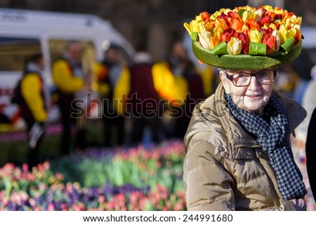 AMSTERDAM, NL - JANUARY 17: Old woman shows a tulip hat on the National Tulip Day in Amsterdam, January 17, 2015. The start of the new tulip season is celebrated with free tulip picking on Dam Square.