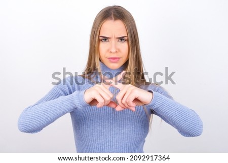 Young caucasian girl wearing blue turtleneck over white background has rejection angry expression crossing fingers doing negative sign. Foto stock © 