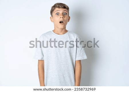 Shocked beautiful kid boy wearing casual grey T-shirt stares bugged eyes keeps mouth opened has surprised expression. Omg concept Foto stock © 