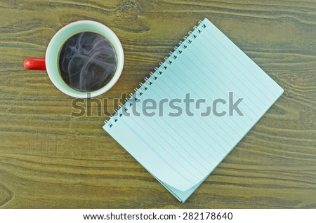 red cup of hot coffee and white sketch book on wood table