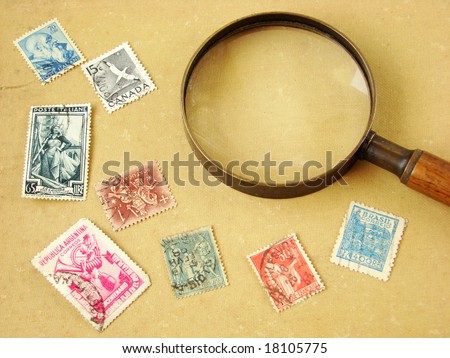 World postage stamps and magnifying glass on old and worn textile background