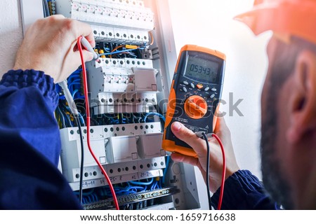 Electrician installing electric cable wires and fuse switch box. Multimeter in hands of electricians detail. Photo stock © 