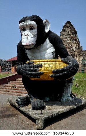Lopburi, Thailand December 29, 2013:  Monkeys scamper around the lawns and stairs and on the base of a giant primate statue at Wat Phra Phang San Yot in Lopburi, Thailand
