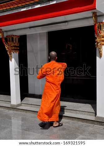 Bangkok, Thailand December 27, 2013:  Buddhist Monk in orange robe entering a pavilion at Wat Chaichana Songkhram in Bangkok, Thailand\'s Chinatown district