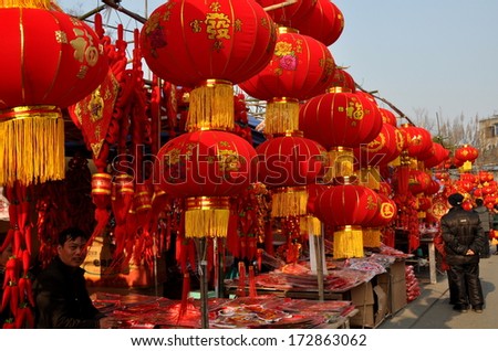 Pengzhou, China January 22, 2014:  Street vendors\' booths selling decorations for the Chinese New Year hung with hundreds of bright red lanterns