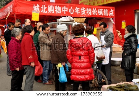 Pengzhou, China January 29, 2014:  People queue to buy specialty foods for the Chinese New Year holiday at a street vendor\'s stand