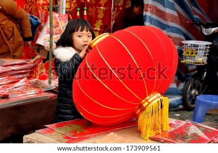 Pengzhou, China January 29, 2014:  Little girl holding a big red Chinese New Year lantern at a vendor\'s booth in Long Xing Square