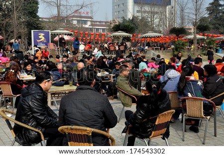 Pengzhou, China February 1, 2014:  Crowds of people sitting outside in Pengzhou City Park decorated with Chinese New Year lanterns drinking tea and playing cards