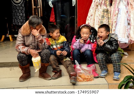 Pengzhou, China January 30, 2014:  Elderly Chinese woman sitting on a step in front of a clothing store with three small children