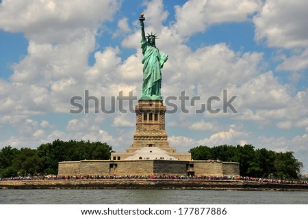 NY - AUG 3, 2013:  The Statue of Liberty standing atop a stone octagonal base with crowds of tourists  *