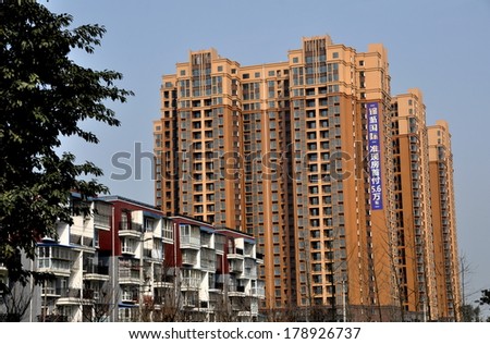 Pengzhou, China- January 25, 2014:  Modern luxury apartment complexes and adjacent townhouses built on former farmlands are indicative of the city's rapid growth and expansion