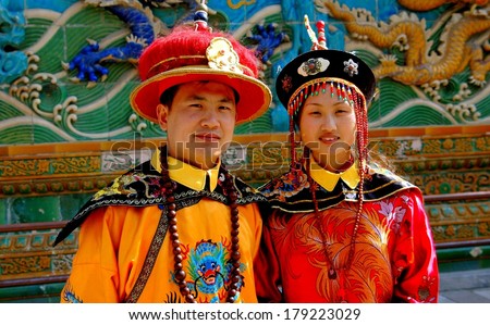 BEIJING - MAY 6, 2005:  A young Chinese couple pose in traditional Mandarin clothing in front of the Dragon Screen Wall at the Summer Palace