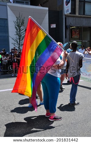 NYC - June 29, 2014:  Woman carrying a large rainbow flag marching in the 2014 Gay Pride Parade on Fifth Avenue