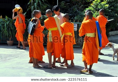 KANCHANABURI, THAILAND - December 26, 2010:  Young monks wearing orange robes gather outside of Wat Chaichumphon Chanasongkhramon on their way to school